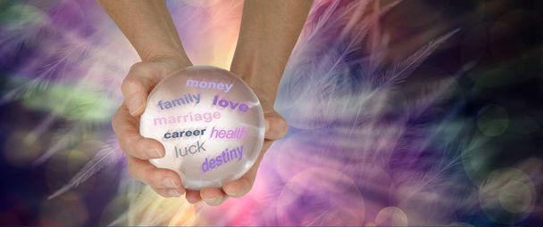 Хрустальный шар может раскрыть многое о вашем будущем - руки, держащие в руках большой прозрачный хрустальный шар, показывающий различные слова на эфирном многоцветном фоне пера с копировальным пространством
 - Фото, изображение