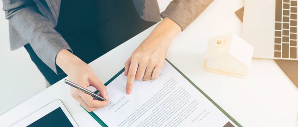 Client signs document regarding real estate activity next to lawyer or real estate agent sitting at office desk. Business concept of selling and buying house. - Photo, Image
