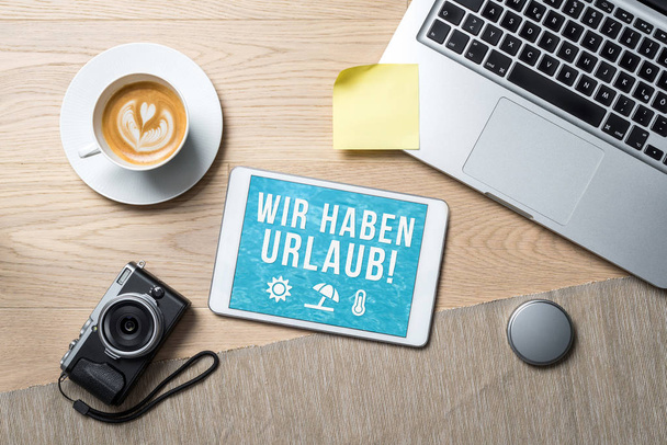 Wir haben Urlaub written in german on tablet meaning company holiday as flatlay from above of an office desk background with notebook - Фото, зображення