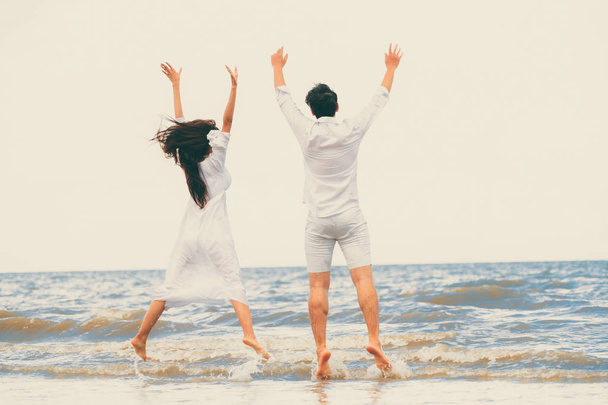 Ευτυχισμένο ζευγάρι πηγαίνει γαμήλια ταξίδια σε τροπική παραλία με άμμο το καλοκαίρι. - Φωτογραφία, εικόνα