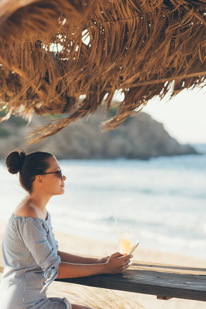 Pretty woman in summer dress drinking cocktail on beach - Foto, Imagen