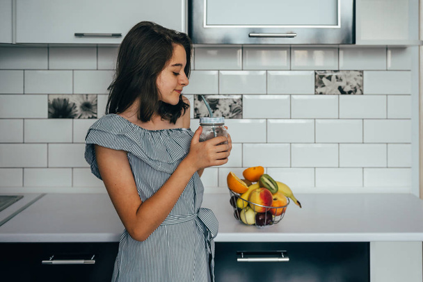Happy young housewife with fruits in modern kitchen. vegetarian food - Photo, Image