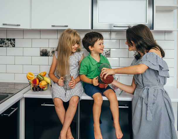 happy family eating fresh fruit. The concept of healthy eating. funny childs with fruits in the kitchen - Φωτογραφία, εικόνα