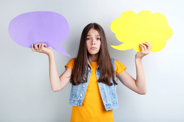 Young girl with speech bubbles on grey background - Fotó, kép