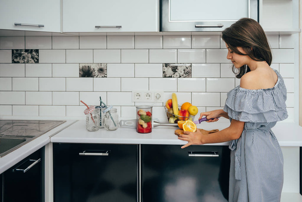 Happy teen girl making fresh juice or meal in a blender in the kitchen. Juice Extractor. Healthy eating concept, vitamins. - Photo, image