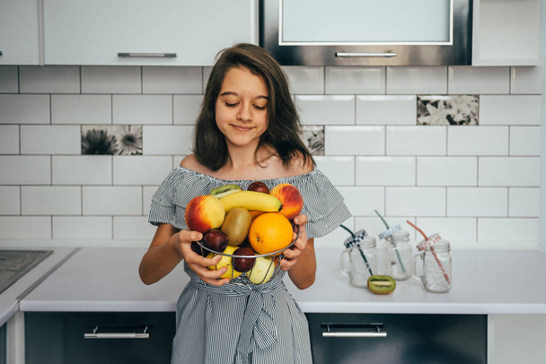 Happy young housewife with fruits in modern kitchen. vegetarian food - Foto, Imagem