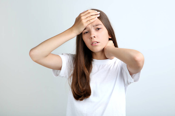 Young girl having headache on grey background - Fotó, kép