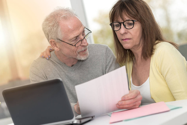Seniorenpaar überprüft Finanzdokument zu Hause, Lichteffekt - Foto, Bild
