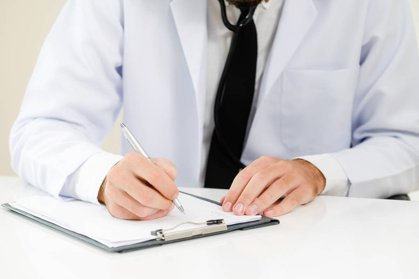 Doctor in hospital working and writing on paperwork. Healthcare and medical service concept. - Photo, image
