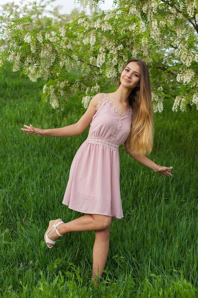 sexy girl with long hair and slender figure standing in green garden in spring - Photo, image