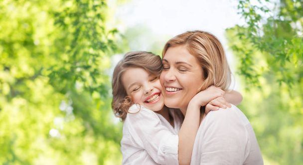 mother and daughter hugging over green background - Photo, image