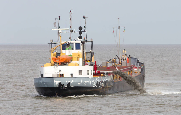 Sand dredging boat drawing away from coast shoreline to pump sand - Waddensea - Foto, immagini