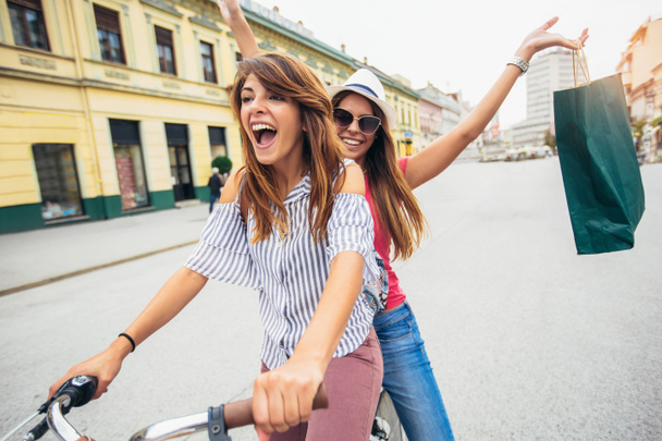 Δύο όμορφες γυναίκες Ψώνια για το ποδήλατο στην πόλη - Φωτογραφία, εικόνα