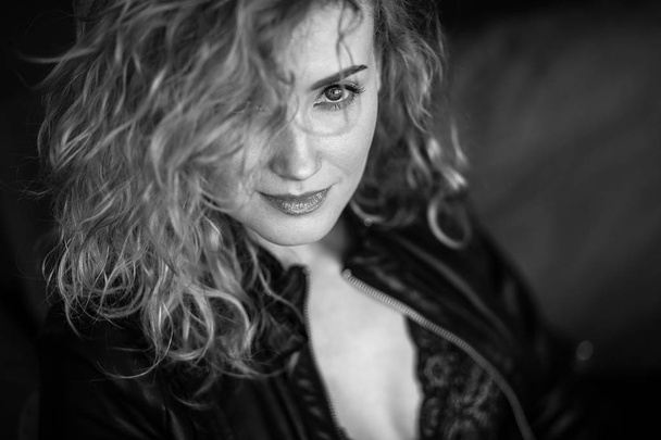 Close-up portrait of sexy blonde woman in a black leather jacket and lacy bra, fashion beauty photo - 写真・画像