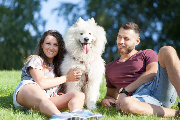 Encantador jovem casal ter tempo de qualidade com seu cão no parque
. - Foto, Imagem