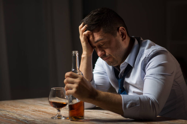 drunk man drinking alcohol at table at night - Foto, Imagen