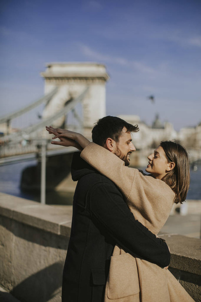ブダペスト、ハンガリーの壮大な景色の背景を抱いて愛の若い幸せな魅力的なカップル - 写真・画像