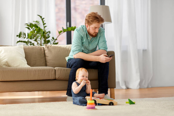father with smartphone and baby playing at home - Fotoğraf, Görsel
