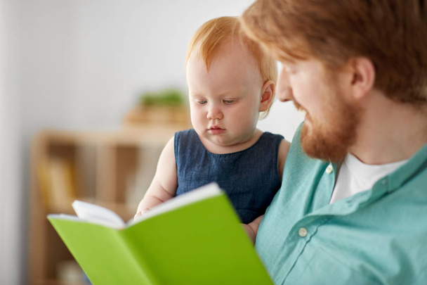 father and baby daughter with book at home - Foto, Bild