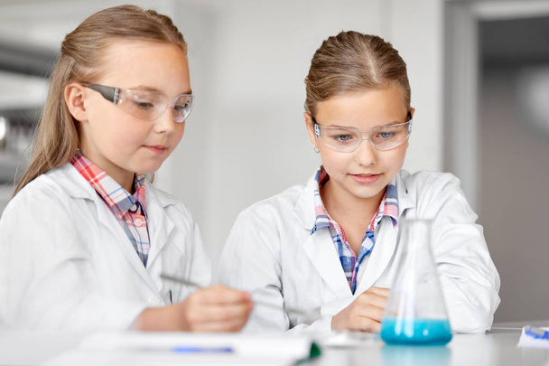 girls with test tube studying chemistry at school - Foto, immagini
