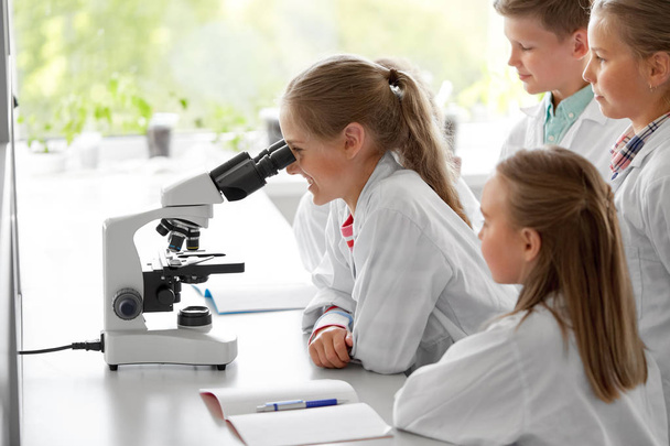 kids or students with microscope biology at school - Foto, afbeelding