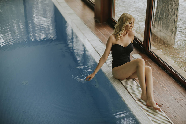 Csinos, fiatal nő relaing, a fedett medence mellett - Fotó, kép