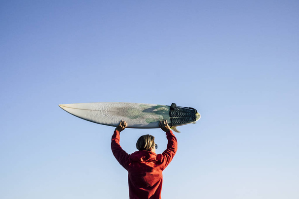 rear view of teen surfer holding surf board over head - Photo, Image