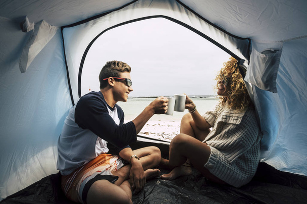 mother and son enjoying camping at beach and drinking coffee - 写真・画像