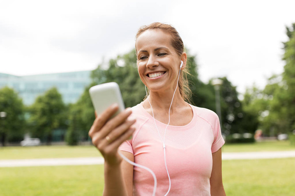 woman listening to music on smartphone at park - Foto, Bild