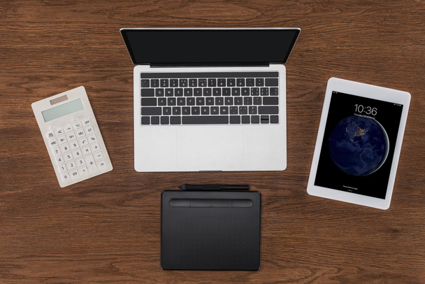 Widok z góry laptopa z pusty ekran, kalkulator, Podręcznik i ipad tablet na drewnianym stole  - Zdjęcie, obraz