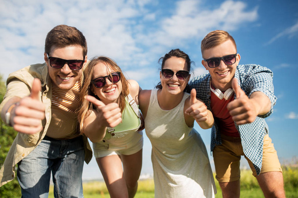happy teenage friends showing thumbs up in summer - Photo, Image