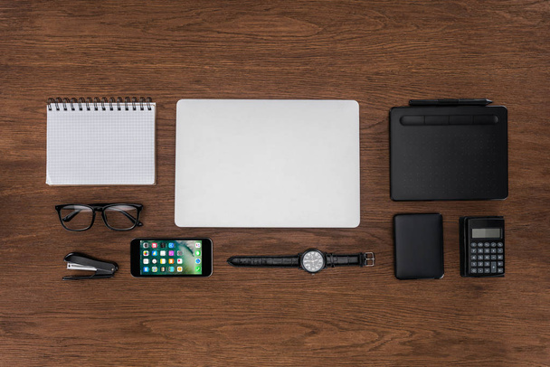 top view of workplace with arranged empty textbook, laptop, wristwatch and iphone on wooden table  - Fotografie, Obrázek
