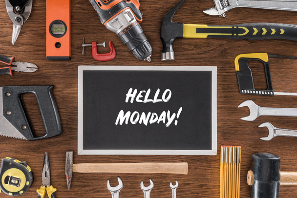 top view of blackboard with lettering hello monday near arranged various tools on wooden table - Фото, зображення