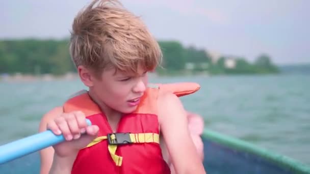 De man drijft op de boot. Tiener opereert zelfstandig een boot met de hulp van de roeiriemen. Extreme sporten - Video