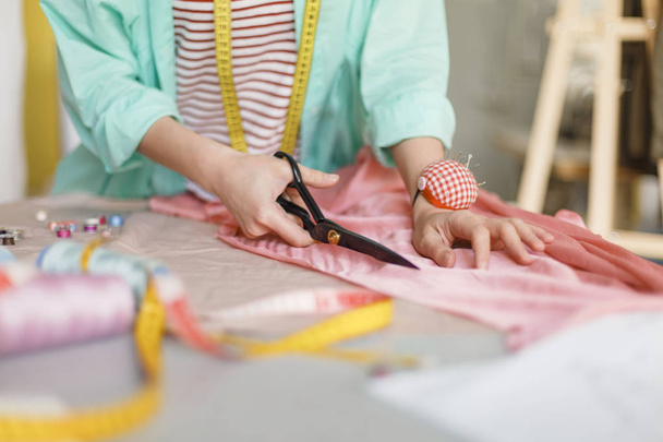 Закрыть ткань для шитья ножницами в современном швейном цехе
 - Фото, изображение