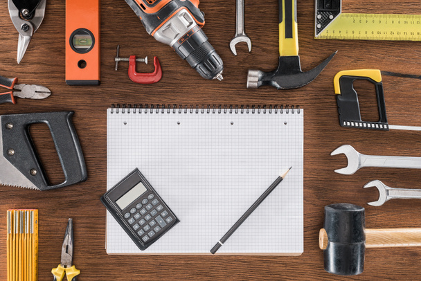 top view of empty textbook, calculator and pencil surrounded by arranged various tools on wooden table - Foto, Imagem