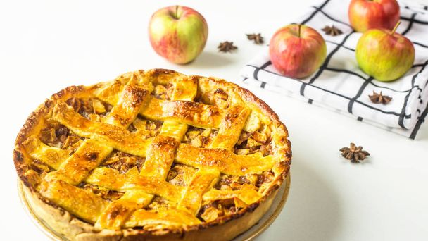 Традиционный американский яблочный пирог с украшением из теста в сетке на белом столе. Концепция осенней выпечки. Минимализм
.  - Фото, изображение