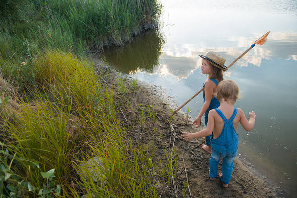 zwei Kinder mit einem Schmetterlingsnetz in der Nähe des Flusses - Foto, Bild