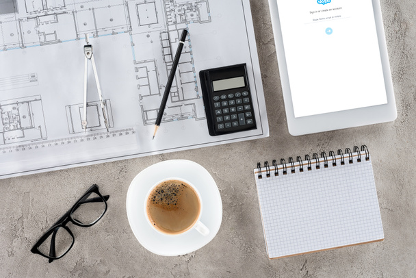 top view of architect workplace with blueprint, divider, coffee and digital tablet with skype on screen - Fotografie, Obrázek