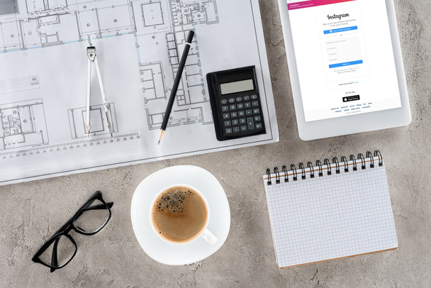 top view of architect workplace with blueprint, divider, coffee and digital tablet with instagram on screen - Фото, изображение