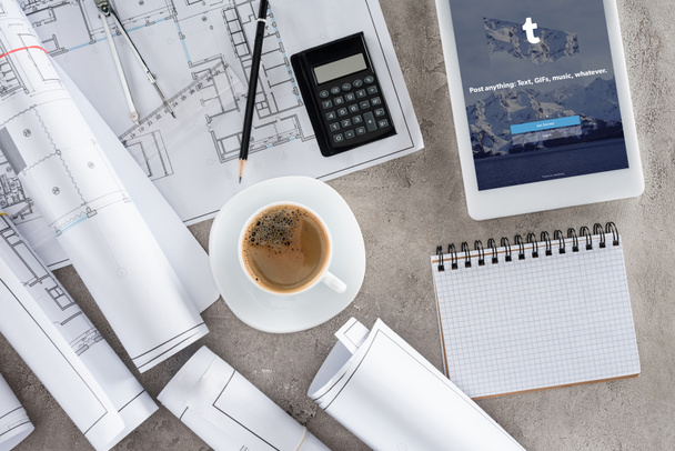 top view of architect workplace with coffee cup, blueprints, calculator and digital tablet with tumblr on screen - Photo, Image