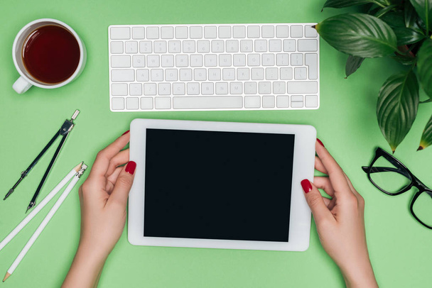przycięty obraz kobiet architekta gospodarstwa cyfrowego tabletu z pustego ekranu przy stole z przegroda, Kawa i roślina doniczkowa  - Zdjęcie, obraz
