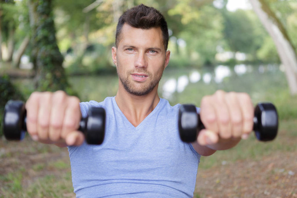 muscular male sportsman training with dumbbells - Фото, изображение