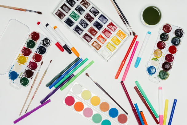 top view of colorful paints, paintbrushes and markers on white table - Foto, immagini