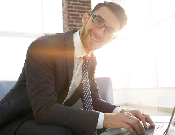 Young businessman using laptop and smiling - Photo, Image