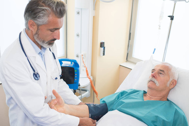 male doctor examining senior man in hospital - Fotoğraf, Görsel