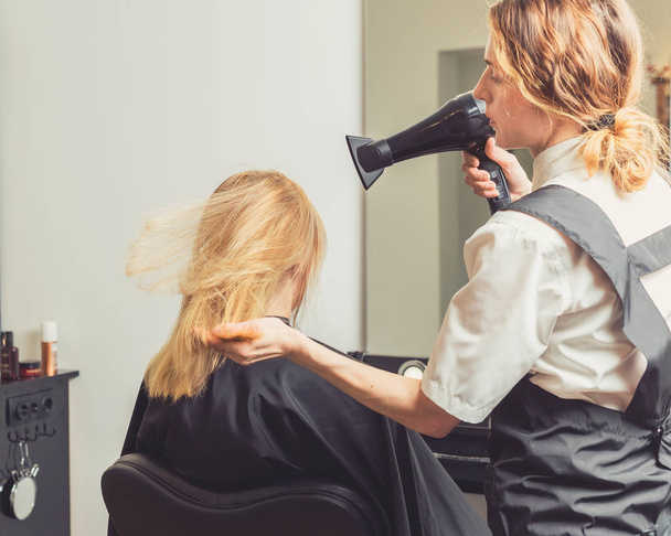 Estetista che asciuga i capelli della donna al salone di bellezza
 - Foto, immagini