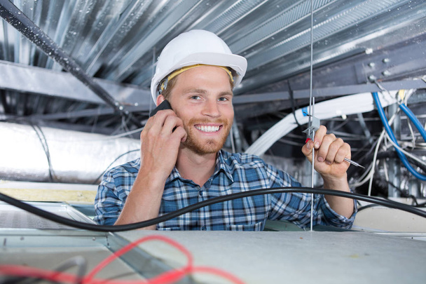cheerful smiling builder working in the ceiling - Foto, Imagem