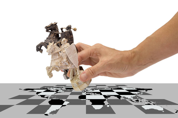 juegos políticos, collage conceptual. mano sostiene dos piezas de ajedrez de un caballo a la vez, colocándolas en un tablero de ajedrez con un mapa del mundo, aisladas sobre un fondo blanco
 - Foto, imagen