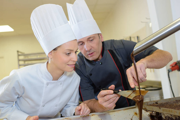 chefs in hotel or restaurant kitchen making chocolate dessert - Foto, Imagen